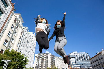 Fototapeta na wymiar Two girls jumping between the city buildings. They are wearing medical masks.