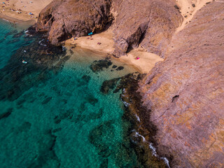 Aerial view of the jagged shores and beaches of Lanzarote, Spain, Canary. Roads and dirt paths. Walking routes to explore the island. Bathers on the beach. Atlantic Ocean. Papagayo