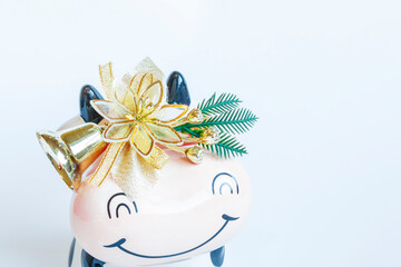 Black and white clay bull figurine decorated with Christmas decorations on a white background. New year of the bull