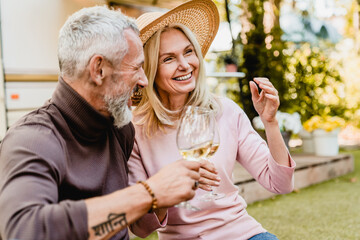 Happy smiling mature couple having romantic picnic and drinking wine in the garden