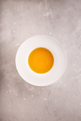 Clear bouillon in white plate on gray background