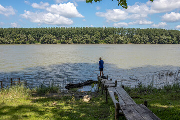 Fototapeta premium Senior man fishing with a fishing rod on the Danube river.