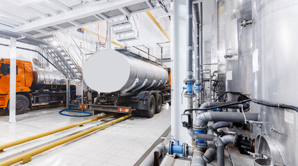 Milk tanker truck pumps products into steel storage tanks, dairy factory industry