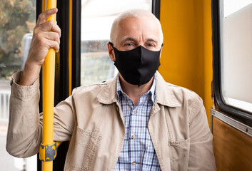 senior man in public transport wearing protective mask - Powered by Adobe