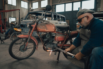 Fototapeta na wymiar Mechanic works a vintage motorcycle in the workshop