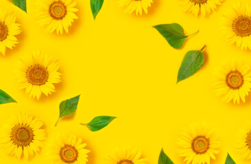 Flower pattern. Frame of beautiful fresh sunflower with green leaves on yellow background. Flat lay...