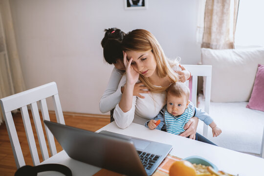 Mother with her baby boy and cute girl working from home