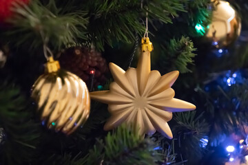 Golden toys on christmas tree branch close up. Balls hanging on pine branches. Christmas background. Festive decoration. Merry Christmas and Happy New Year holiday postcard. Retro style.