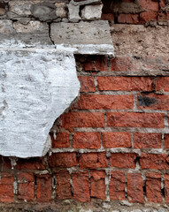 Destroyed gray plaster on a red brick wall. Background