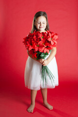 a girl in a white dress with a bouquet of mistletoe looks down at the flowers, isolated on a red background.