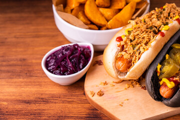 American traditional fast food Hotdog with fresh organic bread bun white wheat and black charcoal sausage ketchup mustard for meal with roasted onion pickle and French fries wedges and coleslaw