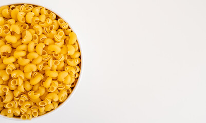 Raw dry uncooked Mini pipe rigate pasta spaghetti noodle on white bowl wooden background for basil...