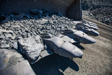Bulldozer bucket steel teeth close up. Quarry and road on background. © Alexey Rezvykh