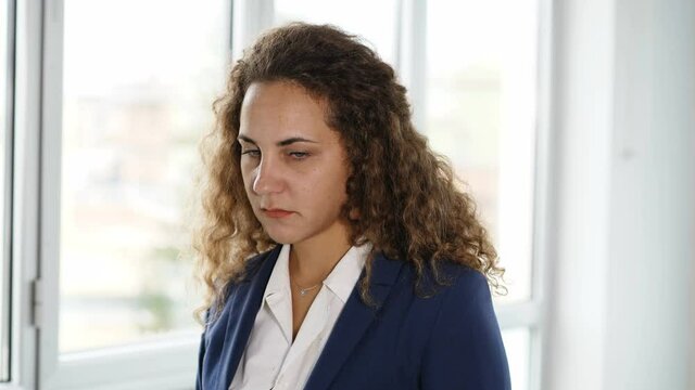 discrimination at work - young worried female manager looks serious at camera 