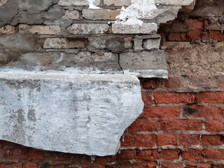 Destroyed gray plaster on a red brick wall. Background
