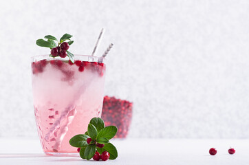 Vitamin autumn fruit drink with lingonberry and ice cubes on white wood board, copy space.