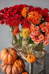 Autumn mood. Set of pumpkins and orange and red flowers for Interior decorations. The work of the florist at a flower shop. Fresh cut flower.