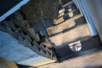 Crashed concrete staircase inside abandoned ruined building. Looking up the ruined weathered multistorey house