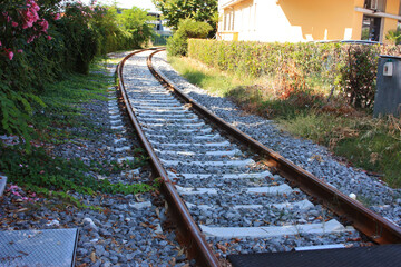 Fototapeta premium gravel and stones along the train tracks next to a house in the green bushes