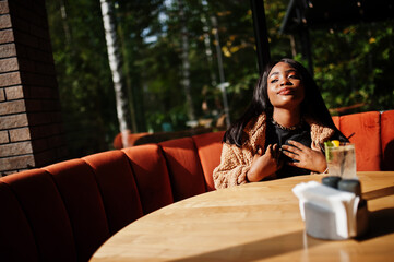 Fashionable african american woman at restaurant drink lemonade.