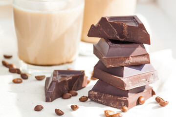 Pieces of dark chocolate, coffee beans and cups of cocoa or coffee with milk on white background. Good morning or happy day concept.