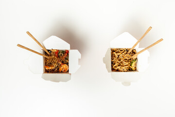 Udon noodles with fried chicken and vegetables in the cardboard box with wooden chopsticks