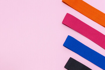 A set of multi-colored elastic rubber bands for fitness on pink background. Fitness trend, sport concept.