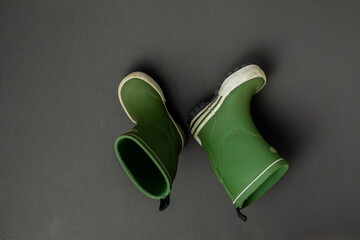 Green rubber boots on grey background.