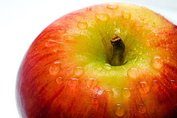Red ripe apple in rain drops on a light background.