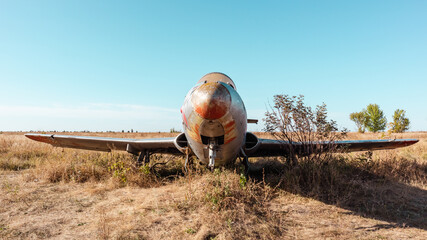 Old military plane front view on blue clear autumn sky background in field. Aero L-29 Delfín a jet-powered trainer aircraft at abandoned Airbase remains in Vovchansk, Ukraine