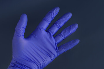 Latex blue medical gloves on a woman's hand on a dark background. Hand protection