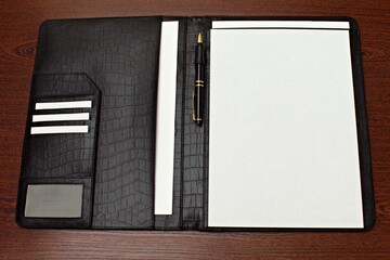 business leather folder with pen and white blank note paper on the table. top view