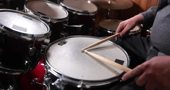 Drumsticks resting on red drums. One single beat is played in slow motion 