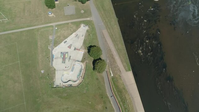 Top down aerial of a skate park beside a murky river