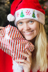 Happy young woman holding a Christmas gift wearing Santa Claus' red hat.