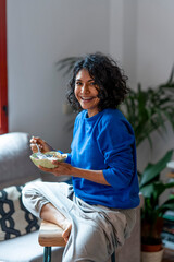 Latin woman having a healthy meal of fruit and yogurt for breakfast.