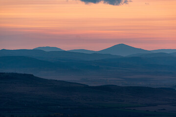Obraz premium Landscape sunset colors over mountains and hills orange red yellow blue shades natural beauty bulgaria rural