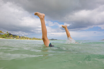 Siblings do synchronized handstands in the ocean with feet showing.