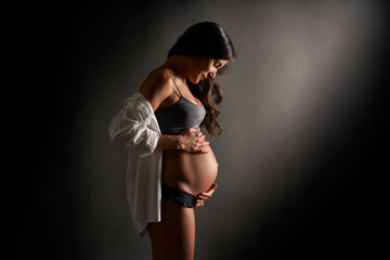 Young pregnant dancer posing holding her belly with her hands