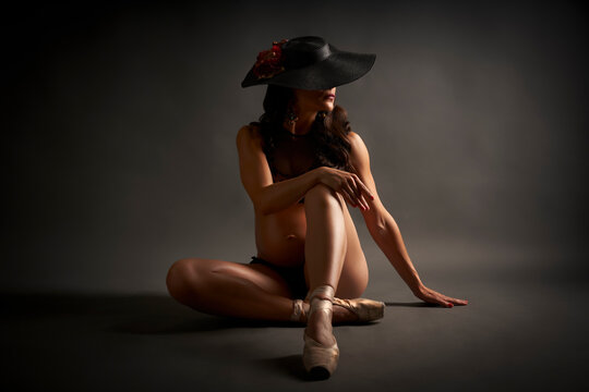 Young pregnant dancer posing with a hat and in black underwear
