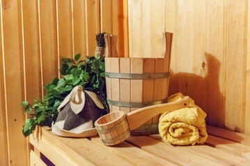 Fototapeta na wymiar Interior details Finnish sauna steam room bathhouse with traditional sauna accessories basin birch broom scoop felt hat towel