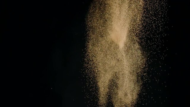 Delicious french dark chocolate truffles exploding with luster cocoa powder dust flying up, slow motion, isolated black background. Handmade chocolate candies, festive sweets, confectionery