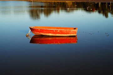 A red old wood boat floating in Lobos lake, Buenos Aires, Argentina.