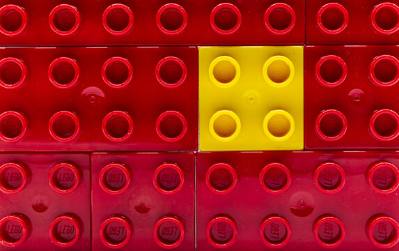 Bologna / Italy - October 27, 2020: Yellow plastic Lego building block surrounded by red ones. Isolation and diversity concept