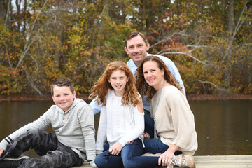 Autumn family portrait by the lake with mom, dad, son and daughter. 