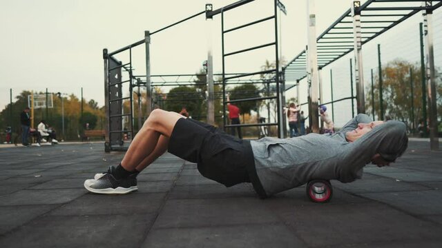 An athlete doing exercises on a foam roller for high-density muscle massage for back pain. Roller for physical therapy trigger point and exercise. Deep tissue massage, pain, yoga, leg muscle