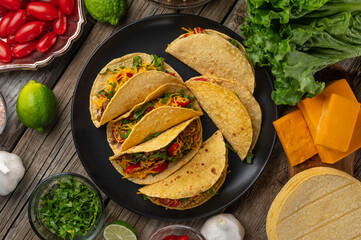 Top view of plate with tasty mexican tacos on rustic wooden table with ingredients for cooking...
