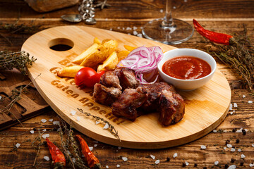 fried meat with sauce and potato garnish on wooden background