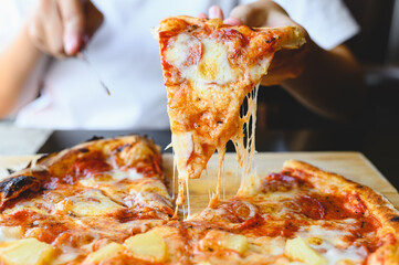 Wood fire cheesy pizza slice in hand. Traditional Hawaiian and Salami pizza savory dish flavour of...