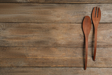 Fork and spoon on wooden table, flat lay with space for text. Cooking utensils